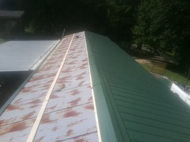 Old rusted panels beside newly installed green metal roofing — Wind Damage Roof Repair by Roofing Brothers in Grapevine