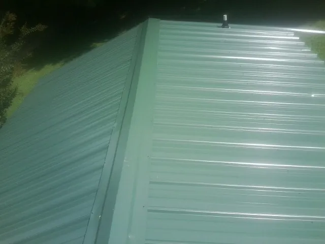New green metal panels meeting at the ridge of a roof — Flat Roof Repair work by our crew in Grapevine