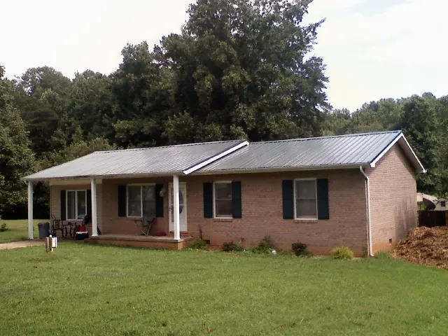 Gray metal roof on a brick ranch house with a side carport in Grapevine