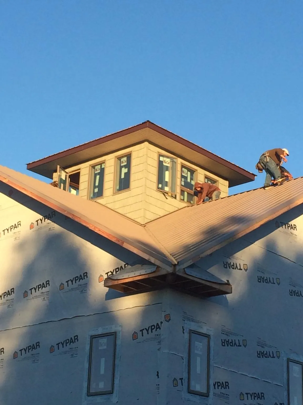 Roofers working around a rooftop cupola on a new metal roof at sunset — Roof Waterproofing in Grapevine by Roofing Brothers